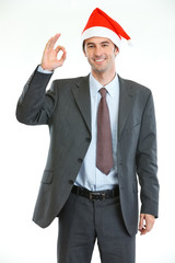 Smiling businessman in Santa's hat showing ok gesture