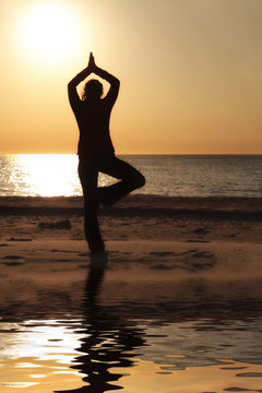 Frau macht Yoga am Strand Baum Position mit Spiegelung © StefanieBaum