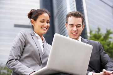 Businessman And Businesswoman Working On Laptop Outside Office