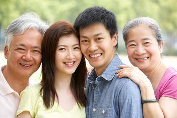 Portrait Of Chinese Parents With Adult Children Relaxing In Park