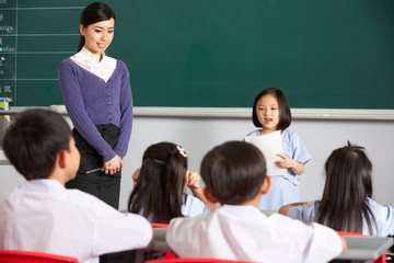 Fototapeta premium Pupil And Teacher Standing By Blackboard In Chinese School
