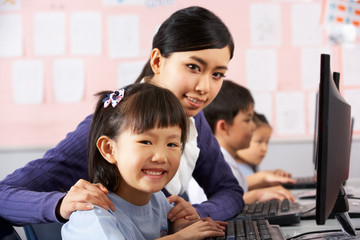 Teacher Helping Student During Computer Class In Chinese School