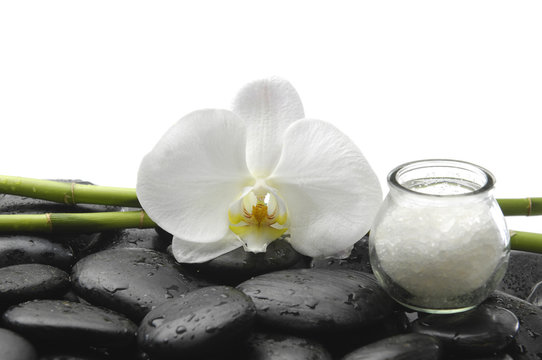 White orchid, salt in glass and bamboo glove on pebbles