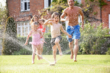 Family Running Through Garden Sprinkler - obrazy, fototapety, plakaty