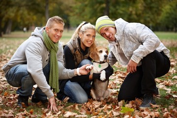 Young people with cute dog in park smiling