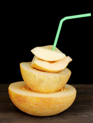 Ripe melons on wooden table on black background
