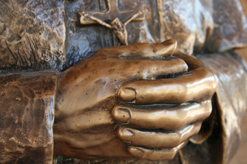 hands of the statue of a priest who pray