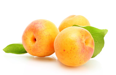 ripe sweet apricots with green leaves isolated on white