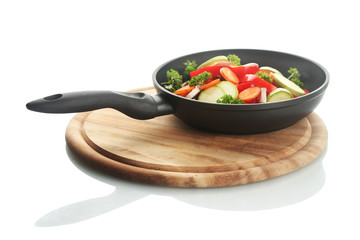 frying pan with vegetables on white