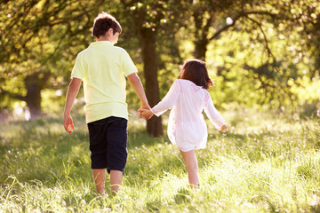 Fototapeta premium Boy And Girl Walking Through Summer Field Together