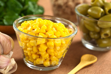 Sweetcorn grains in glass bowl with garlic and olives