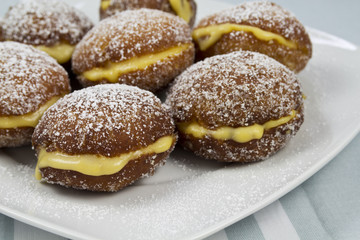 Berliners with cream on a white plate