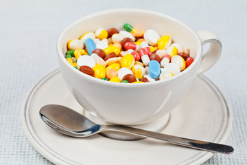 White cup with spoon on the plate filled with medicine pills