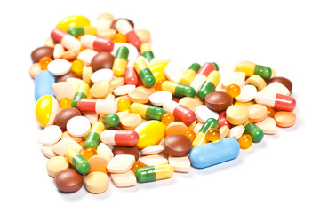 Side view of medicine pills and capsules forming the heart