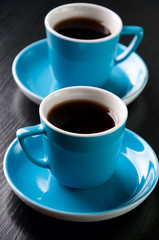 Vertical shot of two turquoise espresso cups on a black table
