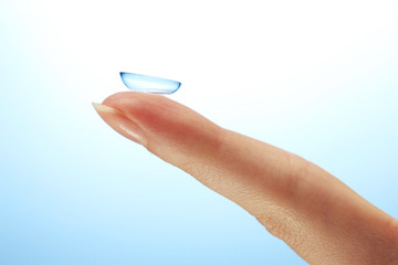 contact lens on finger on blue background