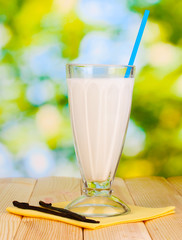 Vanilla milk shake on wooden table on bright background