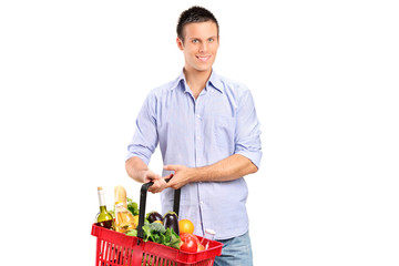Fototapeta na wymiar Smiling man holding a shopping basket full of products