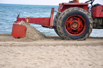 Obraz premium Traktor bearbeitet den Sandstrand