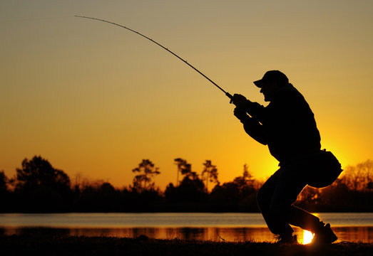 Pêcheur combattant un poisson au soleil couchant