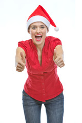 Smiling young woman in Christmas hat showing thumbs up