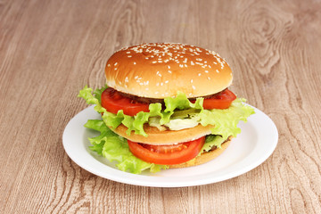 Big and tasty hamburger on plate on wooden table
