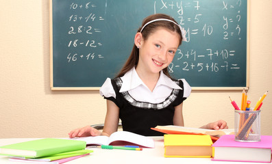 beautiful little schoolgirl in classroom reading the book