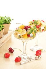 Fresh fruits salad and strawberries on wooden table