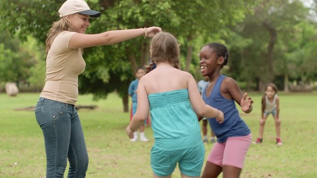 Boys, girls and female educator playing in park