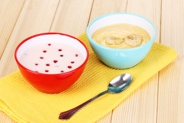 Yogurt with banana and redcurrant on wooden table