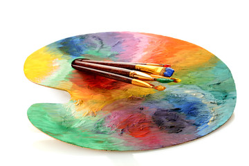 wooden art palette with paint and brushes isolated on white