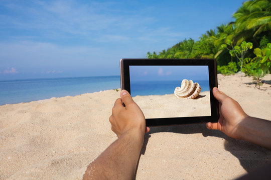 hands holding tablet pc on beach