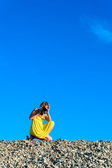 Junge Frau in gelbem Sommerkleid mit Kamera