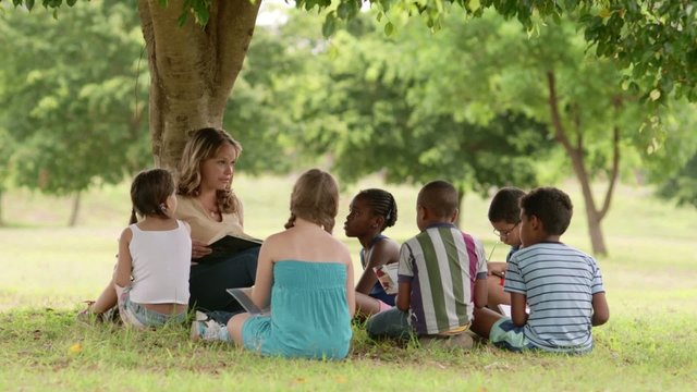 Children and education, teacher reading book to young students