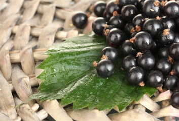 Fresh black currant on wicker mat close-up