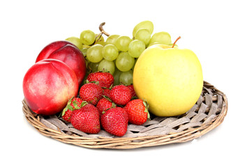 ripe sweet fruits and berries on wicker mat isolated on white
