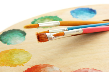 Fototapeta premium wooden art palette with paint and brushes isolated on white