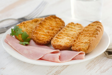 toasts with ham on the white plate