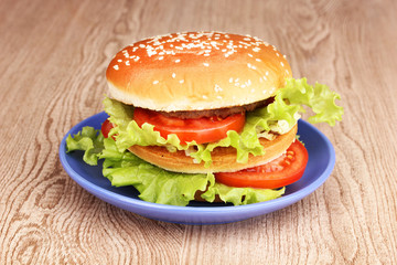 Big and tasty hamburger on plate on wooden table