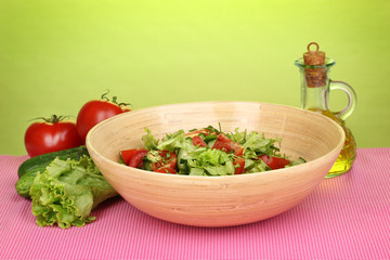 Fresh salad with tomatoes and cucumbers on green background