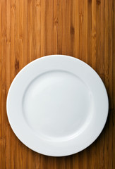 Empty white plate on wooden table