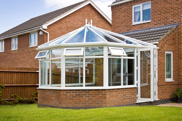 Conservatory with glass roof against a red brick house - obrazy, fototapety, plakaty