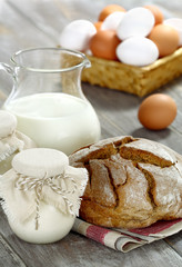 Homemade yogurt, milk, bread and eggs on a wooden table