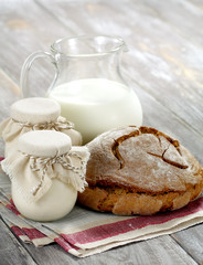 Homemade yogurt, milk and bread on a wooden table