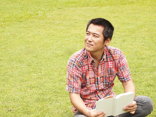 芝生の上で読書をする男性