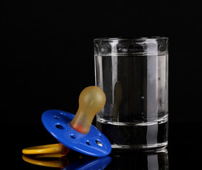 Baby dummy with alcoholic beverage isolated on black