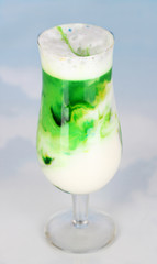 Delicious milk shake with fruit on table on sky background