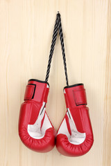 Red boxing gloves hanging on wooden background