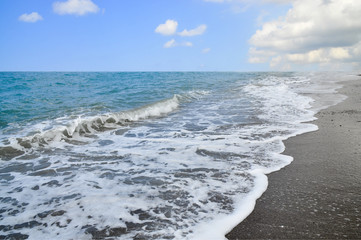 Волны с белой пеной на морском пляже