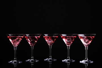 Red cocktail in martini glasses isolated on black
